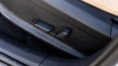 Close-up of black plastic seat adjustment levers on a car seat, set in textured upholstery