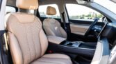 Interior of a car with tan leather seats, front passenger seat in the foreground, center console, and steering wheel.