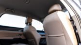 Back seat and front seat headrests of a beige leather car interior, showing door panel and window.