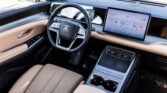 Luxurious car interior with tan perforated seats, a digital dashboard, and a large central touchscreen.