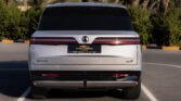 Rear view of a white SUV parked in a lot with palm trees in the background and a Dubai-used car plate.