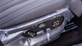 Close-up of a car seat side panel with multiple adjustment switches, wrapped in protective plastic film.