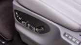 Close-up of a car door panel showing power seat adjustment switches covered with protective tape/plastic wrap by the controls.