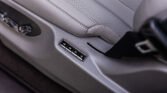 Close-up of a gray perforated car seat and side control panel with adjustment buttons nearby