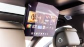 Rear-seat entertainment display in a car showing movie posters and a streaming app interface on the screen