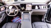 Luxurious car interior focusing on a large central touchscreen and digital dashboard with leather seats and wood trim