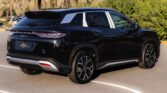 Rear three-quarter view of a shiny black SUV parked in a lot, showing distinctive LED taillights and large alloy wheels.