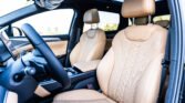 Interior of a car with tan perforated leather front seats and headrests, steering wheel visible on the left.