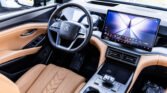 Luxurious car interior with tan leather seats, steering wheel, and a large dashboard touchscreen.