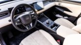 Luxurious car interior with a digital instrument cluster, large center touchscreen, and beige perforated leather seats