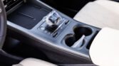 Center console of a car with a wrapped gear shifter, cup holder, and light beige upholstery