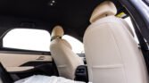 Rear car interior with beige leather seats, headrests, and a bucket-style center console area visible from the back seat.