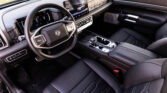 Modern car interior featuring a large central touchscreen, digital instrument cluster, and leather-wrapped steering wheel with silver accents.