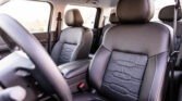 Interior of a car with black leather seats and white stitching, including headrests and seat belts visible in the cabin.