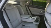 Luxurious car rear seat interior with white leather, center console, and Rolls-Royce headrests visible through the window.