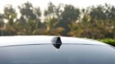 Shark-fin car antenna on the roof of a glossy black car with a blurred green background.