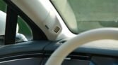 Square microphone mounted on the A-pillar beside the windshield inside a car, for hands-free/voice commands.