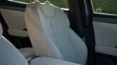 Light beige car seat with diamond perforated pattern and adjustable headrest inside a vehicle interior