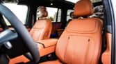 Front interior of a luxury car with orange leather seats and a steering wheel on the left side visible in the foreground.