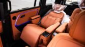 Orange leather car interior with captain's chairs and blue ambient door lighting.