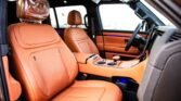Orange leather car interior with front seats, center console, and cup holders; blue ambient lighting visible along door panels