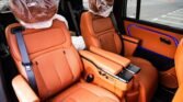 Luxurious orange-brown leather car seats with a center console in a vehicle cabin, blue ambient door lighting nearby.