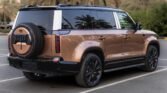 Bronze-colored Range Rover SUV parked in a lot with a spare tire mounted on the rear door.