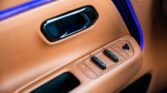 Beige car door panel with power window switches and lock button, illuminated by blue ambient light