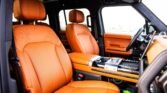 Luxurious car interior with orange leather seats and center console seen from the passenger side interior.
