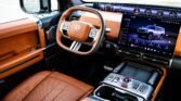 Luxury car interior with orange leather seats, ST-branded steering wheel, and a large touchscreen dashboard.