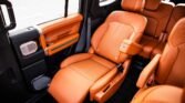 Orange leather car interior with a front captain's chair and orange door panel visible on the left. The rear seats are also orange leather.