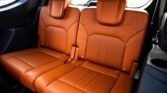 Orange leather rear car seats with two headrests in a vehicle interior, view from the side door panel close-up