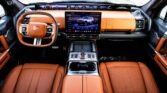 Luxurious car interior with tan leather seats, an illuminated digital dashboard, and a large central touchscreen fueling the cabin.