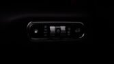 Car interior headlight control panel with auto/off settings and illuminated dials in a dark car cabin