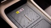 Close-up of a car's center console ashtray tray with a small metallic release handle and warning stickers on the lid.