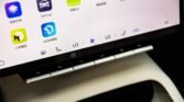 Close-up of a tablet or laptop screen showing colorful app icons (some with Chinese labels) and a row of physical function keys beneath the display.