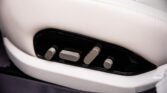 Close-up of stainless steel seat adjustment controls on a white car seat panel in a luxury interior.
