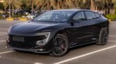 Black luxury sedan parked in a lot with palm trees in the background