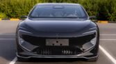 Front view of a sleek black luxury car parked in a lot, with slim LED headlights and a smooth glossy finish on the bumper press area.
