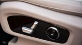 Beige car seat side panel with silver seat adjustment levers and a circular lumbar dial on black trim