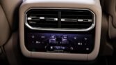 Beige car interior rear HVAC console with a touchscreen climate control panel and horizontal air vents above it