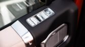 Luxury car door panel with chrome window/lock controls and a large speakers grille below