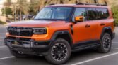 Orange four‑door SUV parked in a lot with palm trees in the background.