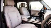 Front interior of a luxury SUV with beige leather seats and a glossy center console.