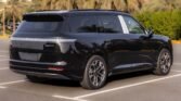 Black SUV parked in a lot, rear three-quarter view with palm trees in the background, glossy finish visible.