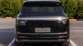 Rear view of a black Lynk & Co 900 EM-P SUV parked in a lot, taillights and license plate area visible. Reflections on the glossy surface are prominent.