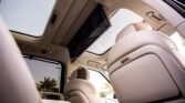 Cream-colored car interior with a mounted rear-seat entertainment screen, sunroof, and plush seats.
