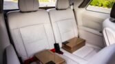 Interior of a light-colored car backseat with two cardboard boxes resting on the seats.
