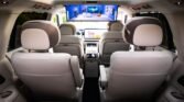 Interior of a white leather SUV with rear captain seats, overhead entertainment screen, and front touchscreen displays.