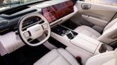 Interior of a white luxury car with a large touchscreen dashboard and white leather seats